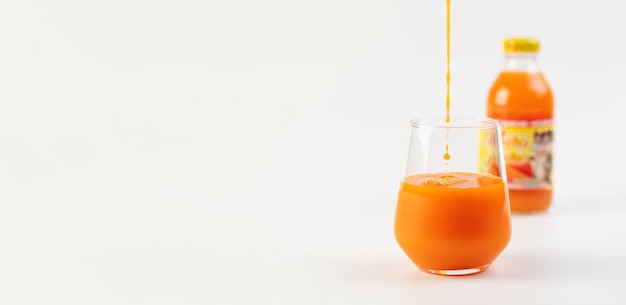 Baner sok jabłkowo-marchewkowy malinowy przelewany do szklanki na białym tle, miejsce na tekst