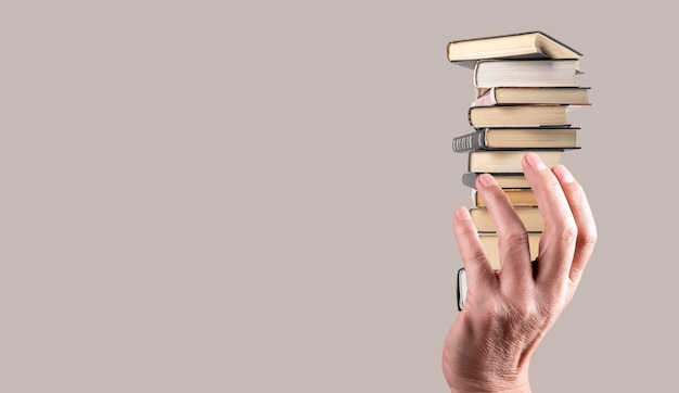 Baner z ręką trzymającą stos książek na szarym tle Wiedza koncepcja mądrości rozwoju intelektualnego Skopiuj miejsce