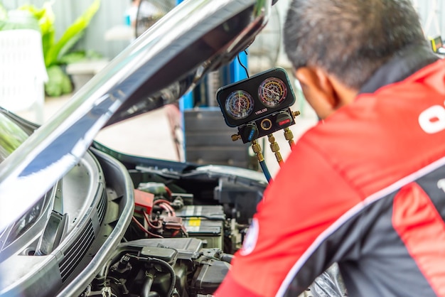 Zdjęcie bangkok 4 maja 2023 nieznany mechanik samochodowy lub serwisant napełniający klimatyzację i sprawdzający kompresor powietrza w celu naprawy i naprawy problemu w garażu samochodowym lub warsztacie naprawczym