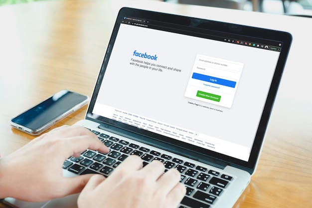 Bangkok. Tajlandia. 1 2021 CZERWIEC Logo aplikacji społecznościowej Facebook przy logowaniu, rejestracja na stronie rejestracji na ekranie aplikacji na laptopach w dłoni osoby biznesowej w kawiarni.