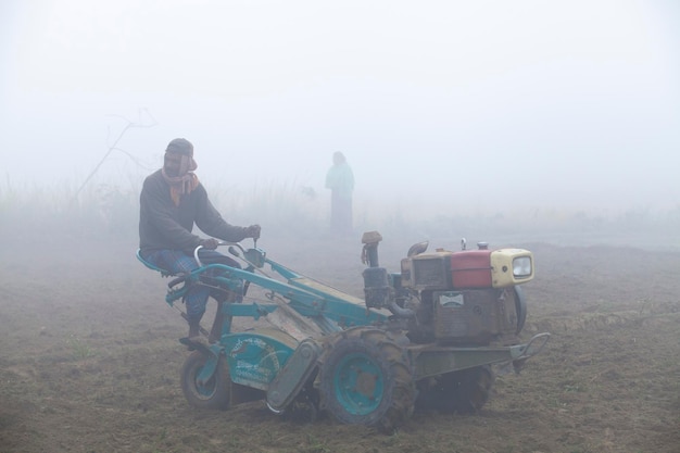 Bangladesz 6 stycznia 2014 W mglisty zimowy poranek rolnik orze swoją ziemię dwukołowym traktorem w Ranisankail Thakurgaon