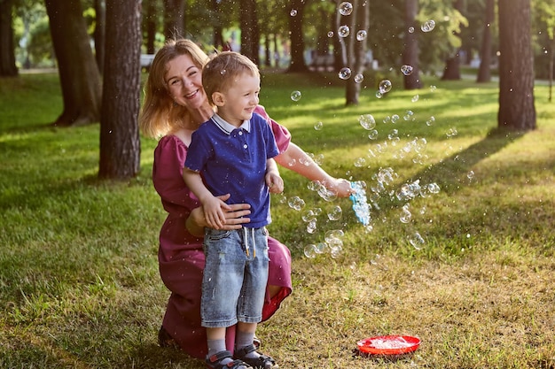 Bańki mydlane jako gra dla uśmiechniętej mamy i synka w publicznym parku.