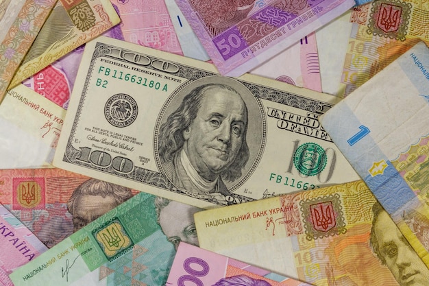 Banknot studolarowy na tle banknotów hrywny ukraińskiej