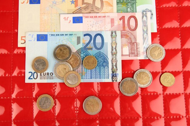 Banknoty euro i centy euro na czerwonym tle