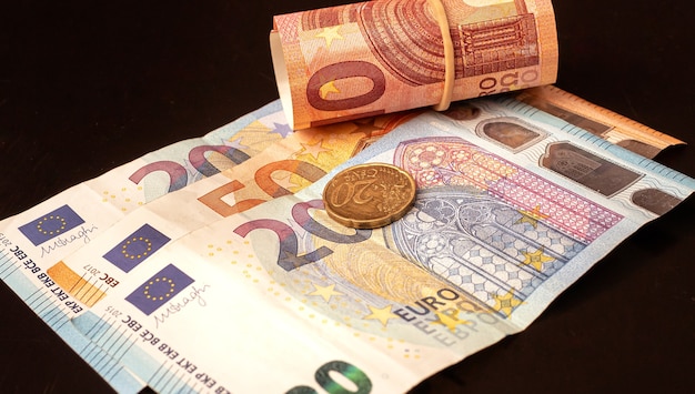 banknoty euro i pojedyncza moneta na biurku w ciemnym kolorze