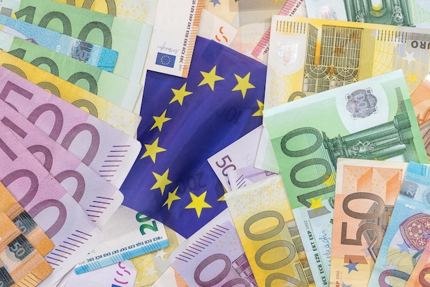 banknoty euro na narodowej fladze europejskiej w tle