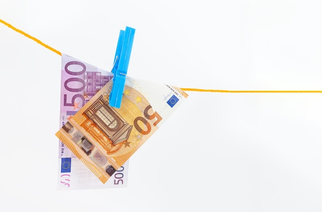 banknoty euro przymocowane spinaczami do bielizny na linie na białym tle