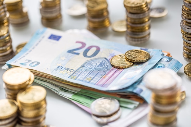Banknoty i monety euro razem na białym stole - zbliżenie.