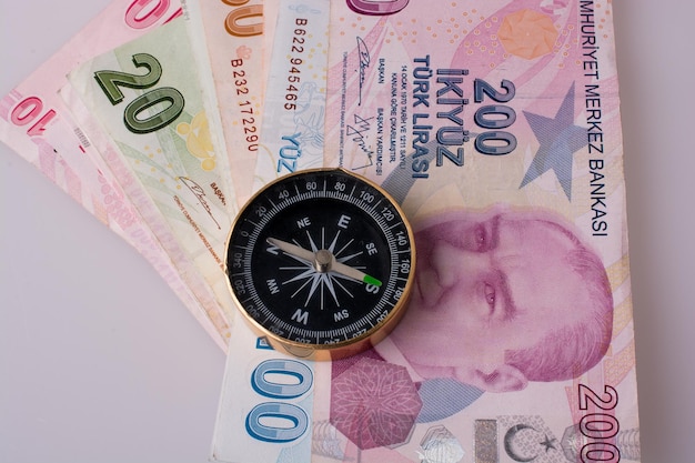 Banknoty liry tureckiej obok kompasu na białym tle