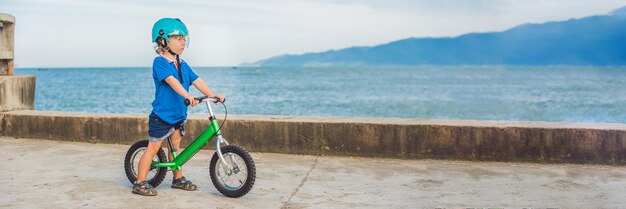 Banner aktywny blond dziecko chłopiec jazdy rowerem w parku w pobliżu morza maluch dziecko marzy i