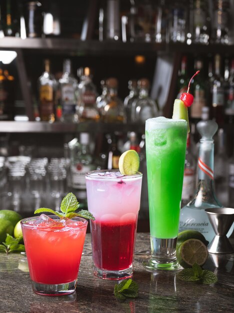 Zdjęcie bar z trzema koktajlami, z których jeden ma na ladzie zielony napój.