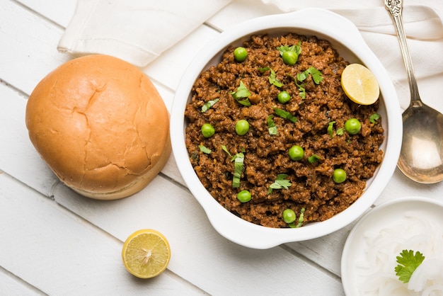 Baranina Kheema Pav Lub Indyjskie Pikantne Mięso Mielone Podawane Z Chlebem Lub Kulcha, Przyozdobione Zielonym Groszkiem. Nastrojowe Tło. Selektywne Skupienie