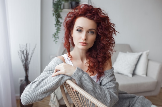 Bardzo atrakcyjna młoda kobieta w pomieszczeniu. Portret kobiety kręcone włosy. Redhaired piękna kobieta w domu.