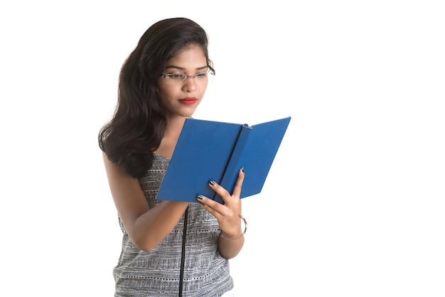 Bardzo młoda dziewczyna trzyma książkę i pozowanie na białej ścianie