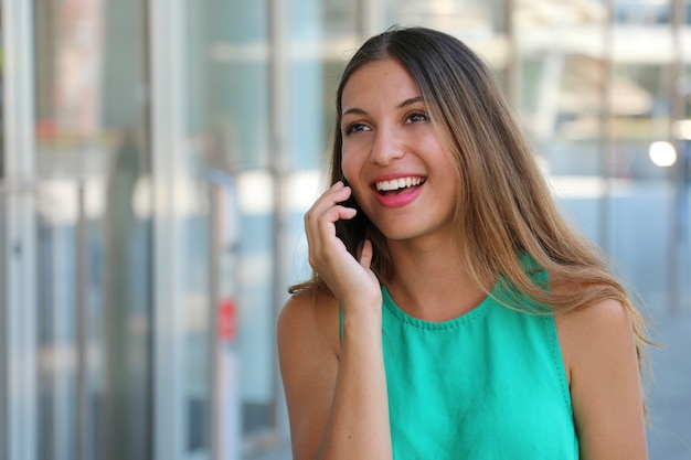 Bardzo młoda kobieta dzwoniąc z inteligentnego telefonu na zewnątrz