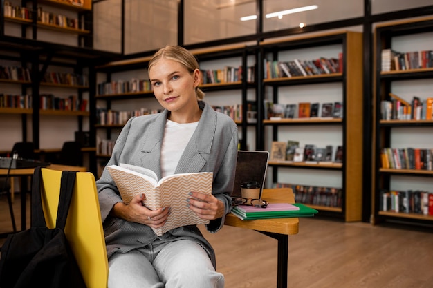 Bardzo młoda kobieta pozuje w bibliotece