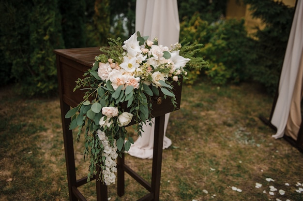 Bardzo piękna ceremonia zewnętrzna. klasyczny ślub w lesie. Łuk jest drewniany. Białe kwiaty. Brązowe krzesła. Obrzęd. Panna młoda i pan młody Dekoracje. Florystyka. Na świeżym powietrzu.