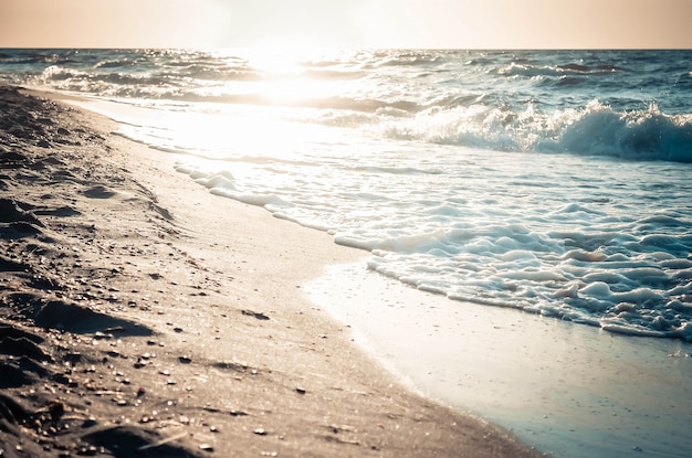 Bardzo piękne odbicie słońca w mokrym piasku nad brzegiem morza, stonowane i filtrowane