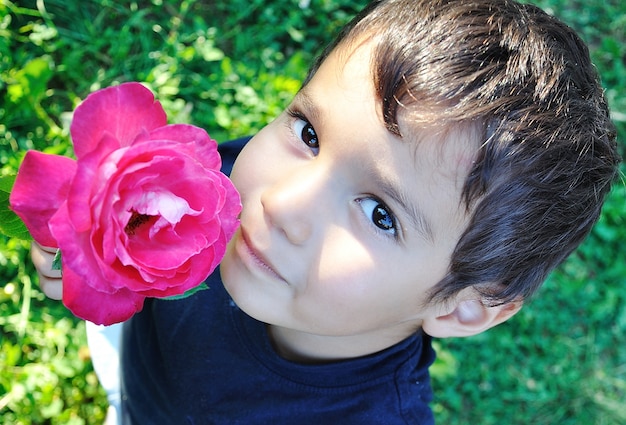 Bardzo słodkie dziecko z różową różą w ręku