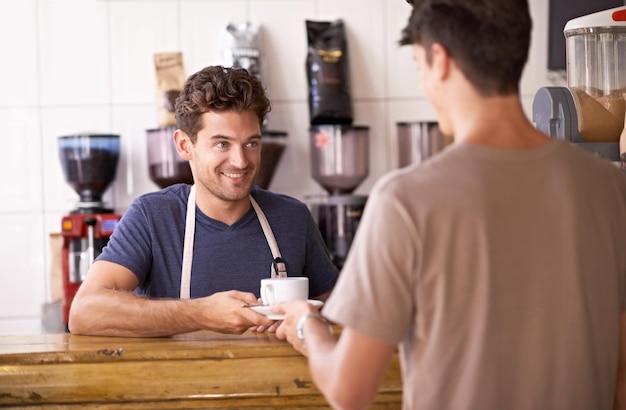 Barista i filiżanka w kawiarni obsługująca klientów i pracująca w restauracji lub małym przedsiębiorstwie Mężczyzna przedsiębiorca i ekspert kawy w bistro zaufanie i przyjazność w gościnności