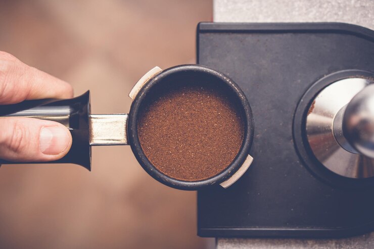 Zdjęcie barista manipuluje kawą w kolbie za pomocą sabotażu zbliżenie procesu przygotowywania świeżej kawy