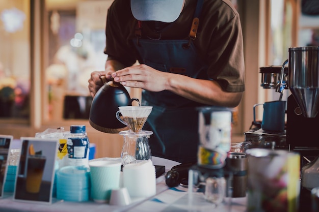 Barista nalewa gorącą wodę, aby zrobić kawę kroplową