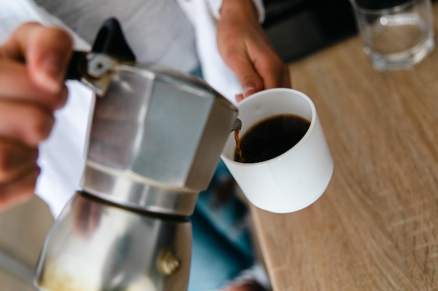 Barista nalewa kawę do filiżanki