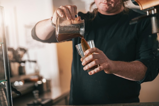 Barista nalewa świeżo przygotowaną kawę do szklanek w kawiarni