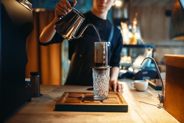 Zdjęcie barista nalewa wodę z dzbanka do szklanki