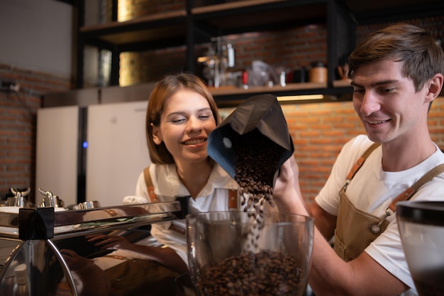 Barista napełnia młyn do kawy prażonymi ziarnami kawy, aby przygotować kawę dla klientów