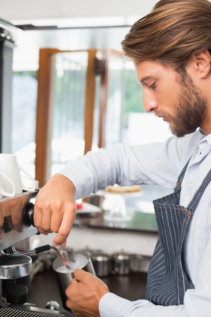 Barista parze mleko w ekspresie do kawy