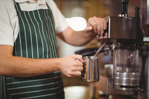 Barista parze mleko w ekspresie do kawy