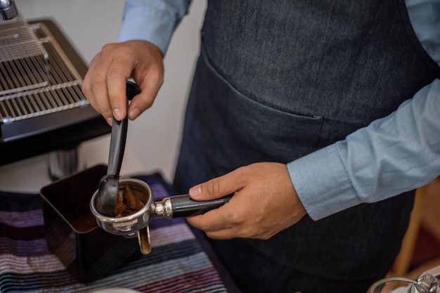 Barista przygotowuje kawę, wciskając zmieloną kawę do pojemnika na kawę