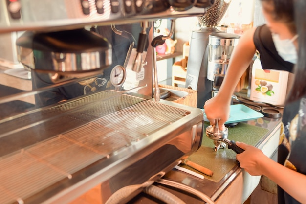 Barista robi kawę latte art z ekspresem do kawy w kawiarnianym odcieniu vintage