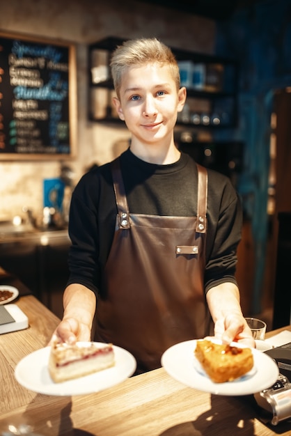 Barista trzymając w rękach talerze ze słodkim deserem