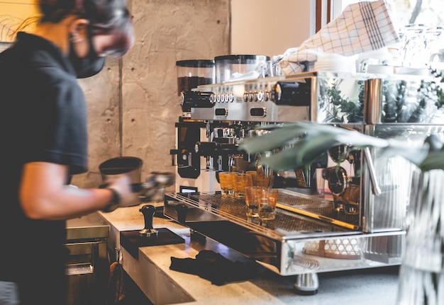 Barista używa ekspresu do kawy w kawiarni