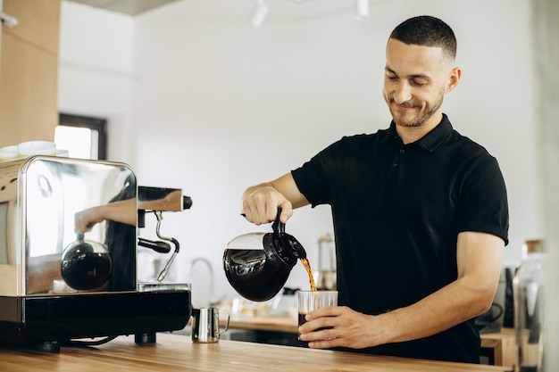 Barista w kawiarni nalewa kawę do szklanki