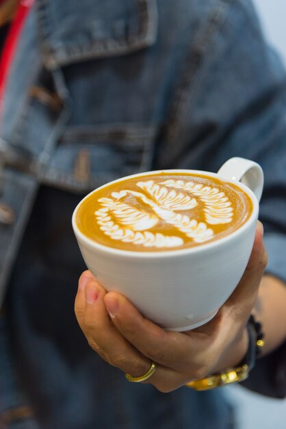 Barista wlewa piana latte, aby zrobić kawową latte art do białej filiżanki
