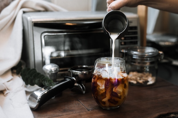 Zdjęcie barista wlewający mleko do szklanki mrożonej kawy