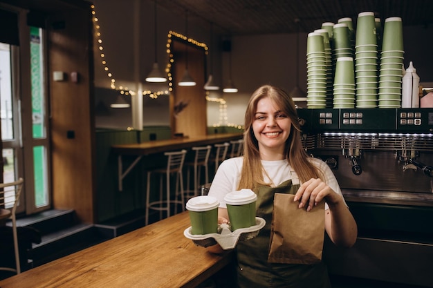 Barista z kawą na wynos i deserem w zbliżeniu kawiarni