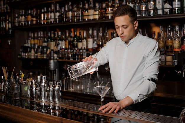 Barman Brunet dodaje napój alkoholowy do kieliszka martini