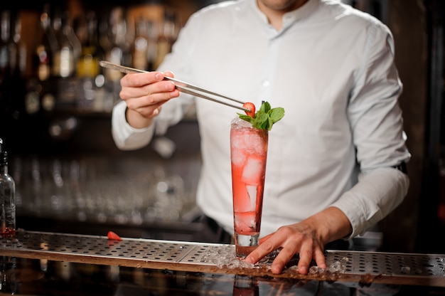 Barman Dekorujący Szklankę świeżego I Słodkiego Truskawkowego Koktajlu Mojito Z Jagodą