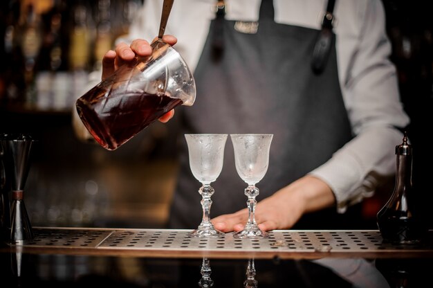 Barman nalewa do szklanki świeżego letniego koktajlu Arnaud