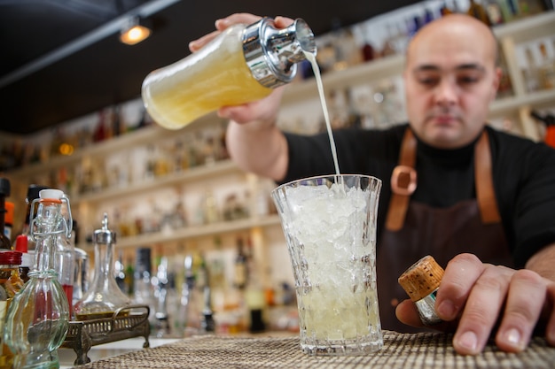 Barman nalewa koktajl do szklanki przy barze