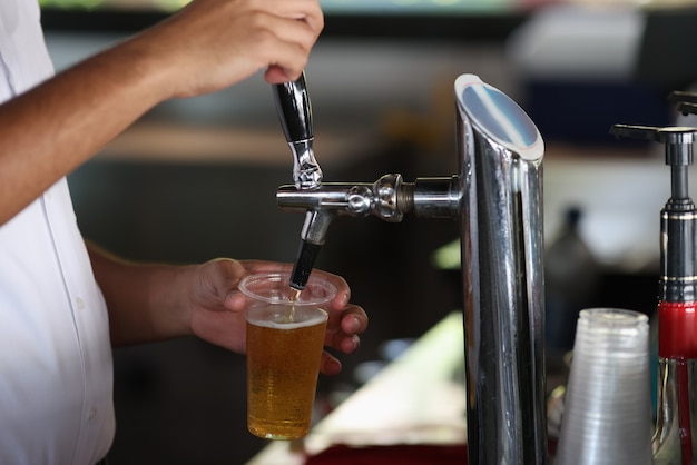 Barman nalewa zimne piwo z automatu do szklanki