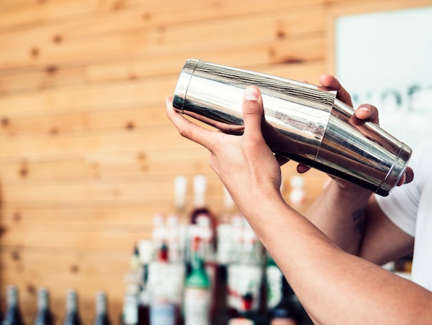 Zdjęcie barman przygotowuje koktajl w shakerze
