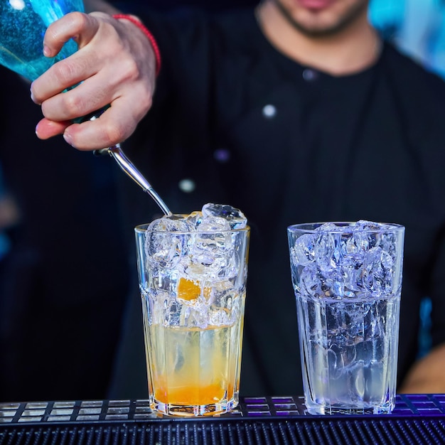 Barman przygotowuje koktajle alkoholowe na ladzie barowej