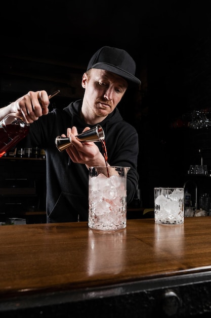 Barman przygotowuje tradycyjny koktajl Negroni w barze Barman miesza gin campari i słodki wermut, aby przygotować koktajl alkoholowy Negroni