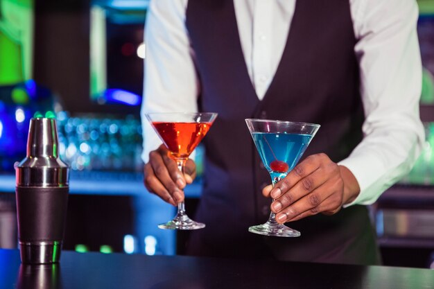 Barman serwuje niebieskie i pomarańczowe napoje koktajlowe w barze w barze