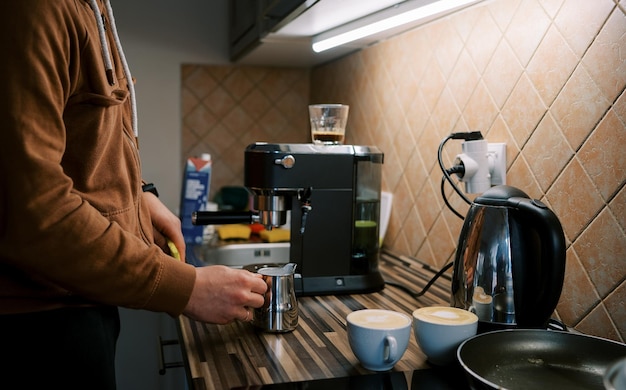 Barman uderza dzbanek z mlekiem na stół, aby osadzić piankę po pianiu mleka